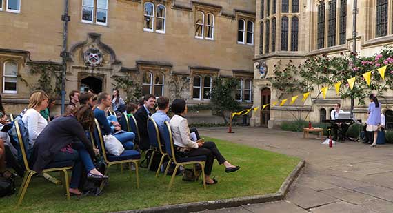 People gathered outside sitting on chairs to watch a performance