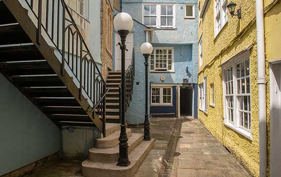 A courtyard of colourful buildings with metal stairs and a lamppost