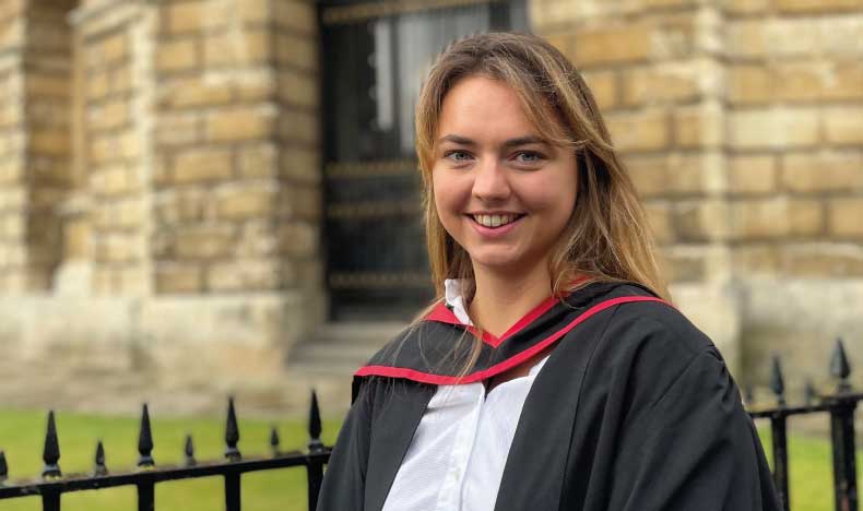 A woman with long light brown hair wearing an academic gown