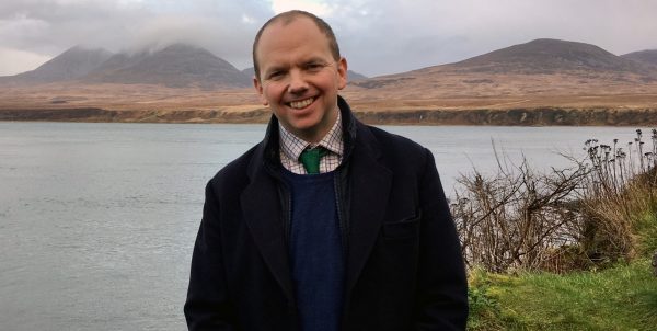 Lord Cameron standing in front of a lake.