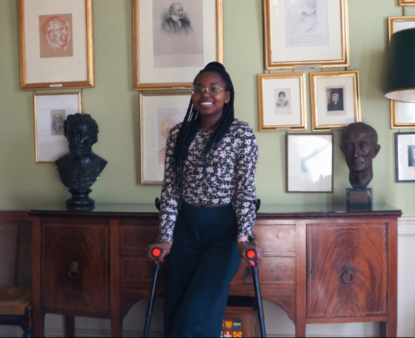 Patricia Mativo standing in front of portraits of Orielenses in the Oriel College SCR.