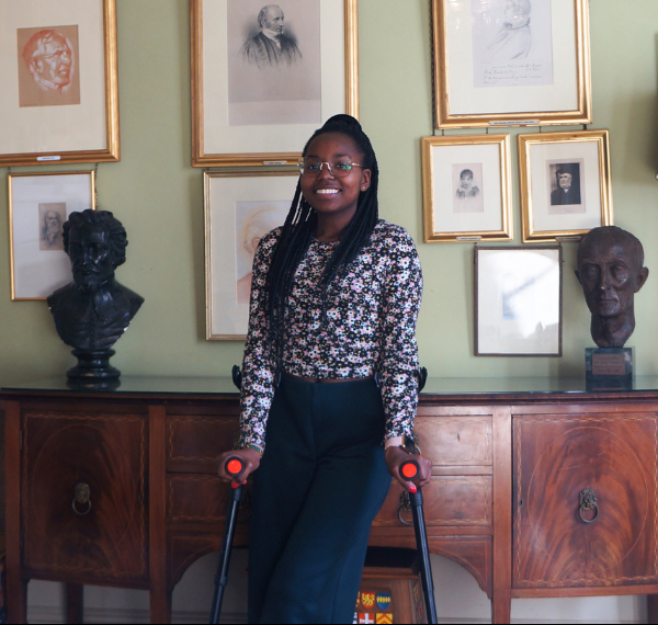 Patricia Mativo standing in front of portraits of Orielenses in the Oriel College SCR.