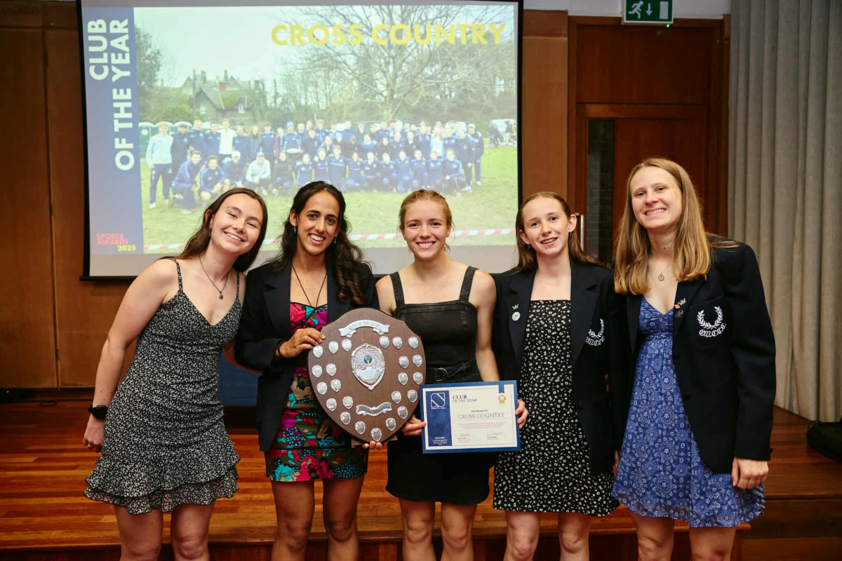 Five women smile for a photo, holding an award and certificate.